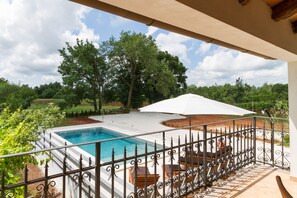 A pool area with a view of the surrounding landscape, including trees and a clear sky.