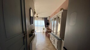 A narrow hallway with a radiator, a mirror, and a dining area with chairs and a table. - 2* Apartment with garden, air conditioning, near the pond in Balaruc-les-Bains (Balaruc-les-Bains)