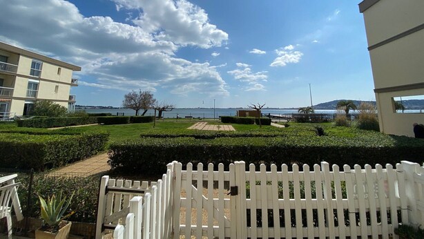 A residential area with a white picket fence, a well-maintained garden, and a view of the sea. - 2* Apartment with garden, air conditioning, near the pond in Balaruc-les-Bains (Balaruc-les-Bains)