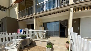 A residential building with a balcony, outdoor seating area, and a white picket fence. - 2* Apartment with garden, air conditioning, near the pond in Balaruc-les-Bains (Balaruc-les-Bains)