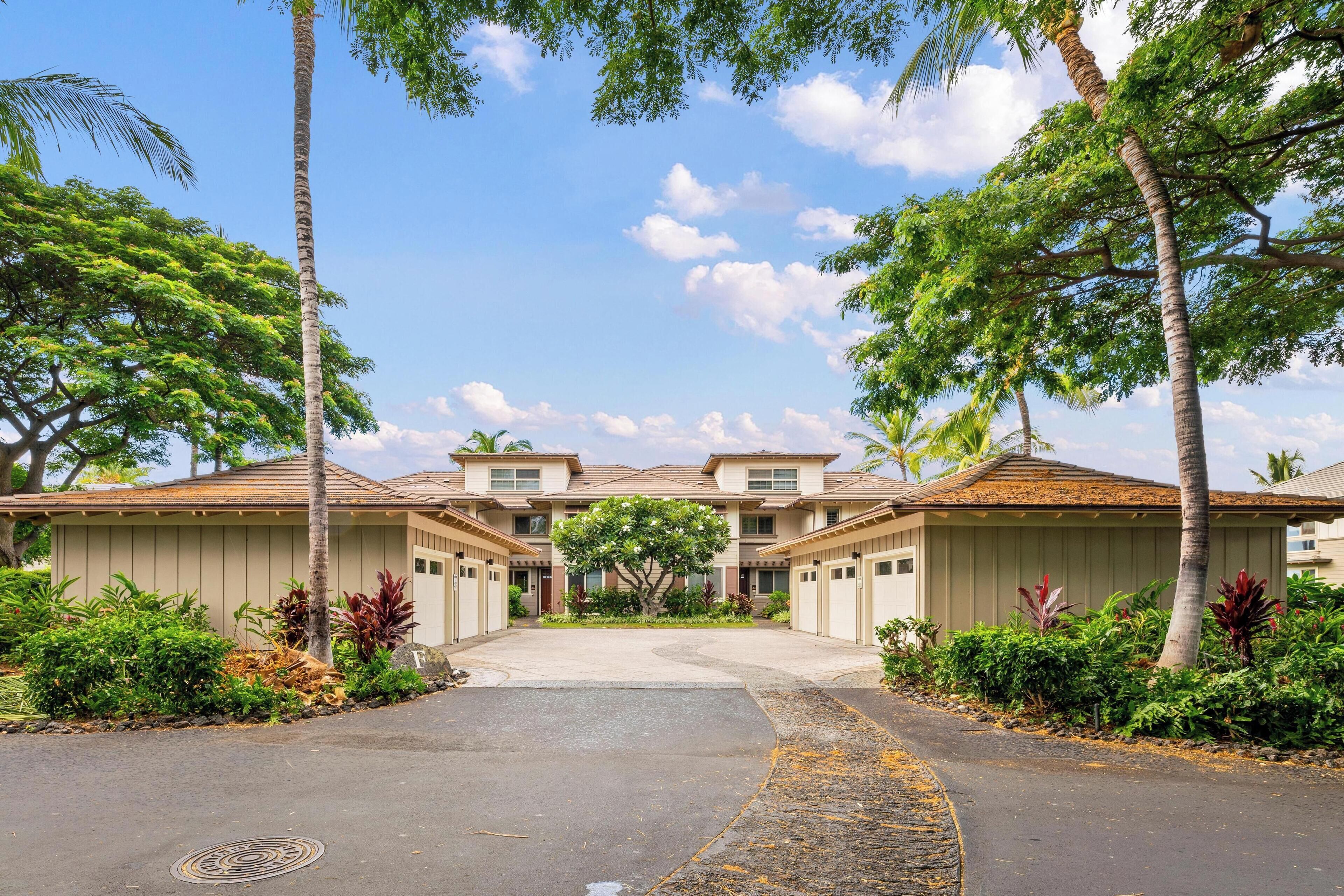 A residential building with a central courtyard, surrounded by lush greenery and palm trees.