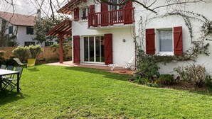 A two-story house with a balcony, a patio with outdoor furniture, and a well-maintained lawn. - Charming 3-Star Beach House, Ideal for Families, with Garden and Parking (Hendaye)
