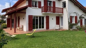 A two-story house with a balcony, a covered patio, and a well-maintained lawn. - Charming 3-Star Beach House, Ideal for Families, with Garden and Parking (Hendaye)