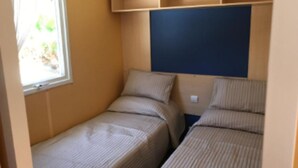 A small room with two beds, a window, and a blue wall.