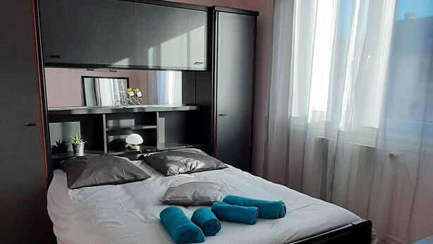 A bedroom with a bed, a bedside table, a mirror, and a ceiling light.
