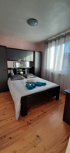 A bedroom with a bed, a bedside table, a mirror, and a ceiling light.