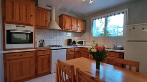 A kitchen with wooden cabinets, a white stove, a microwave, a dishwasher, and a dining table with chairs.
