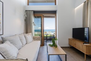 Relax in this stylish living room with a sofa, coffee table, and flat-screen TV, offering a view of the sea.