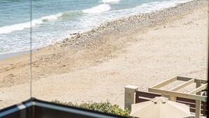 A beach view with a clear sky, a sandy shore, and a distant cityscape with buildings and a dome structure. - North Coast Seaside Suites (Rethymno)