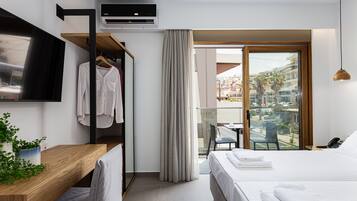 Habitación de hotel moderna con cama, escritorio, televisión, perchero y balcón con vista a la ciudad.