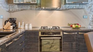 Een moderne keuken met een stenen muur, roestvrijstalen apparatuur en een centraal eiland met een kom fruit.