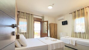 A hotel room with two beds, a wardrobe, a television, and a small table with a remote control. - Cesmeli Boutique Hotel (Cesme)
