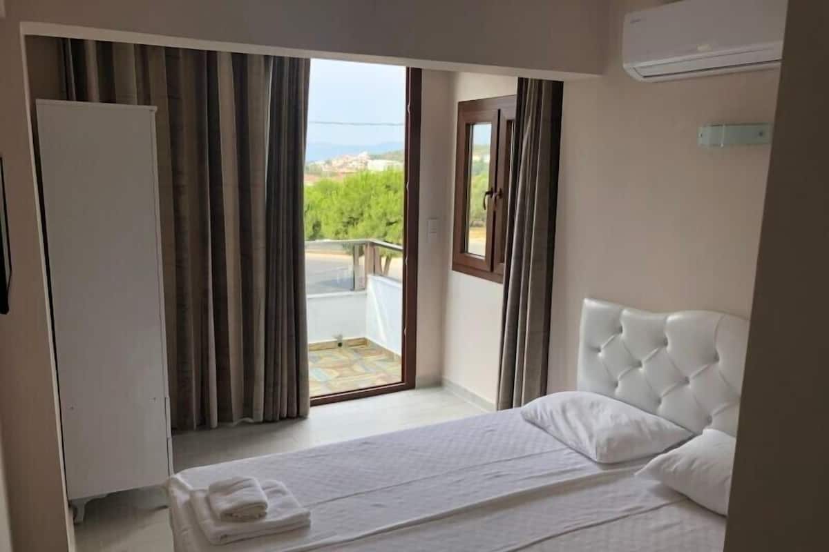 A hotel room with a bed, a wardrobe, and a balcony with curtains.