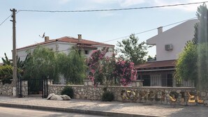 A street view with a building that has a stone wall and a metal gate. - Cesmeli Boutique Hotel (Cesme)