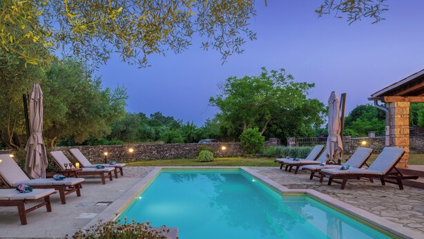 A rectangular pool with a stone border, surrounded by lounge chairs with umbrellas, and a stone wall in the background. - House 1993/28059 (Istria - Rakalj), 900m from the beach (Rakalj)