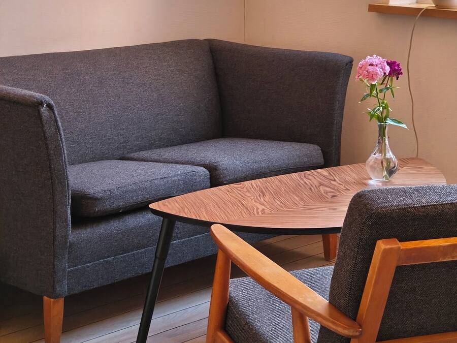 Una habitación con un sofá gris, una mesa de madera y un florero con flores.