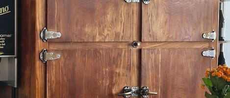 A wooden cabinet with metal hinges and a wooden countertop with a brass bell.