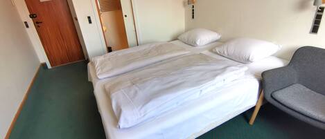 Habitación de hotel con una cama, una silla y una puerta que da a un armario.