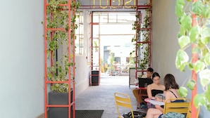 An indoor seating area with red metal railings, potted plants, and a neon sign. - YellowSquare Milan (Milan)