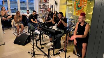 Un grup de persones en una habitació amb instruments musicals, un teclat i un cartell a la paret.