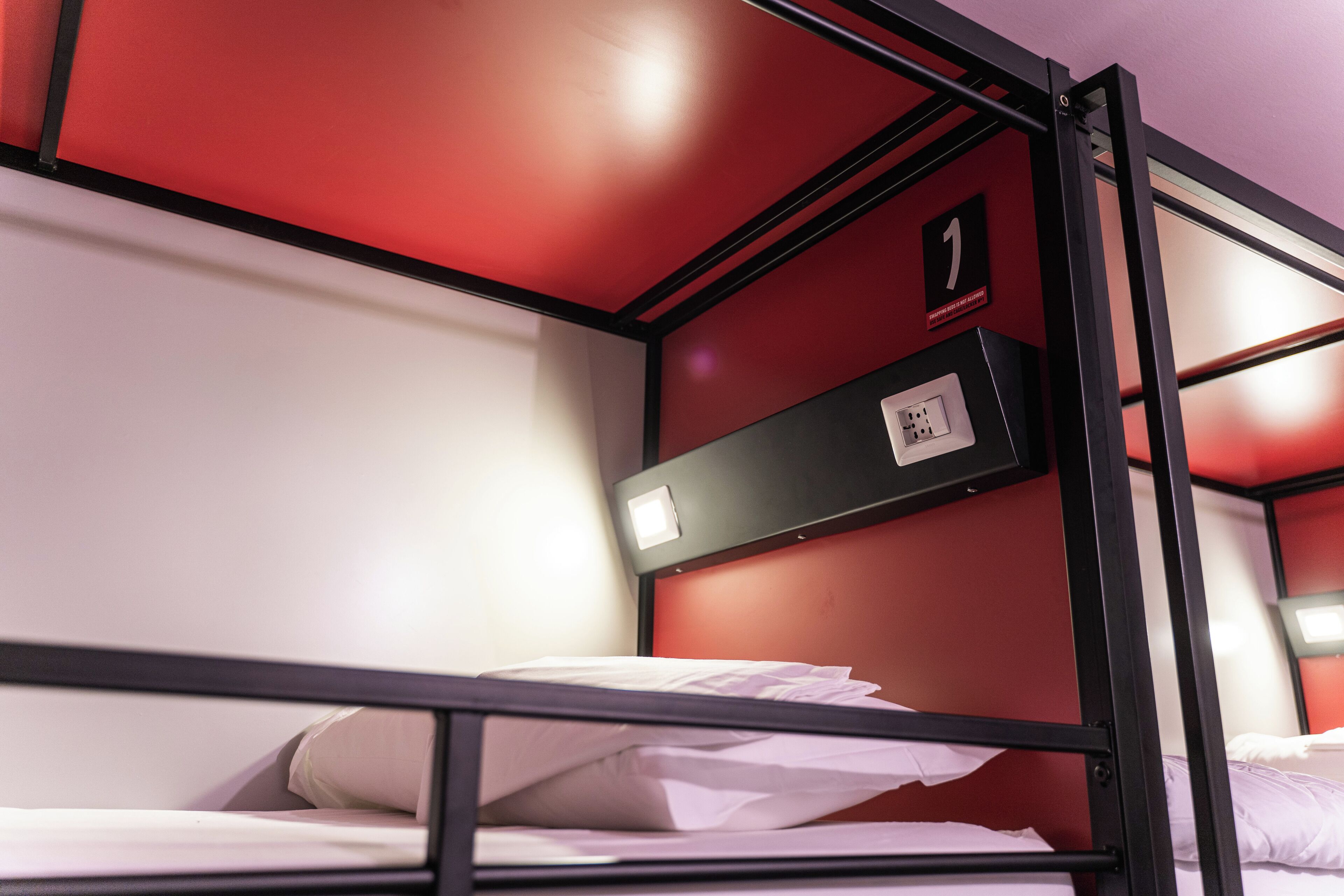 A bunk bed with a red wall and a black metal frame.