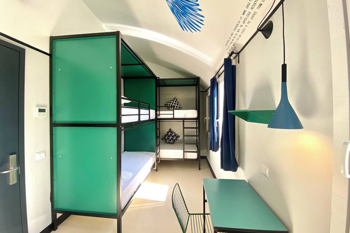A compact hotel room with bunk beds, a small table, and a desk.