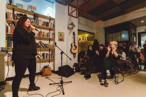 Una habitación con una estantería, una guitarra y un soporte para micrófono.