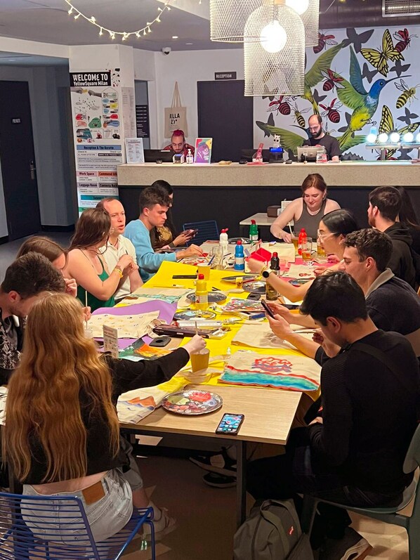 Un groupe de personnes est assis autour d’une table, devant laquelle se trouvent divers objets, notamment des papiers, un ordinateur portable et des boissons.