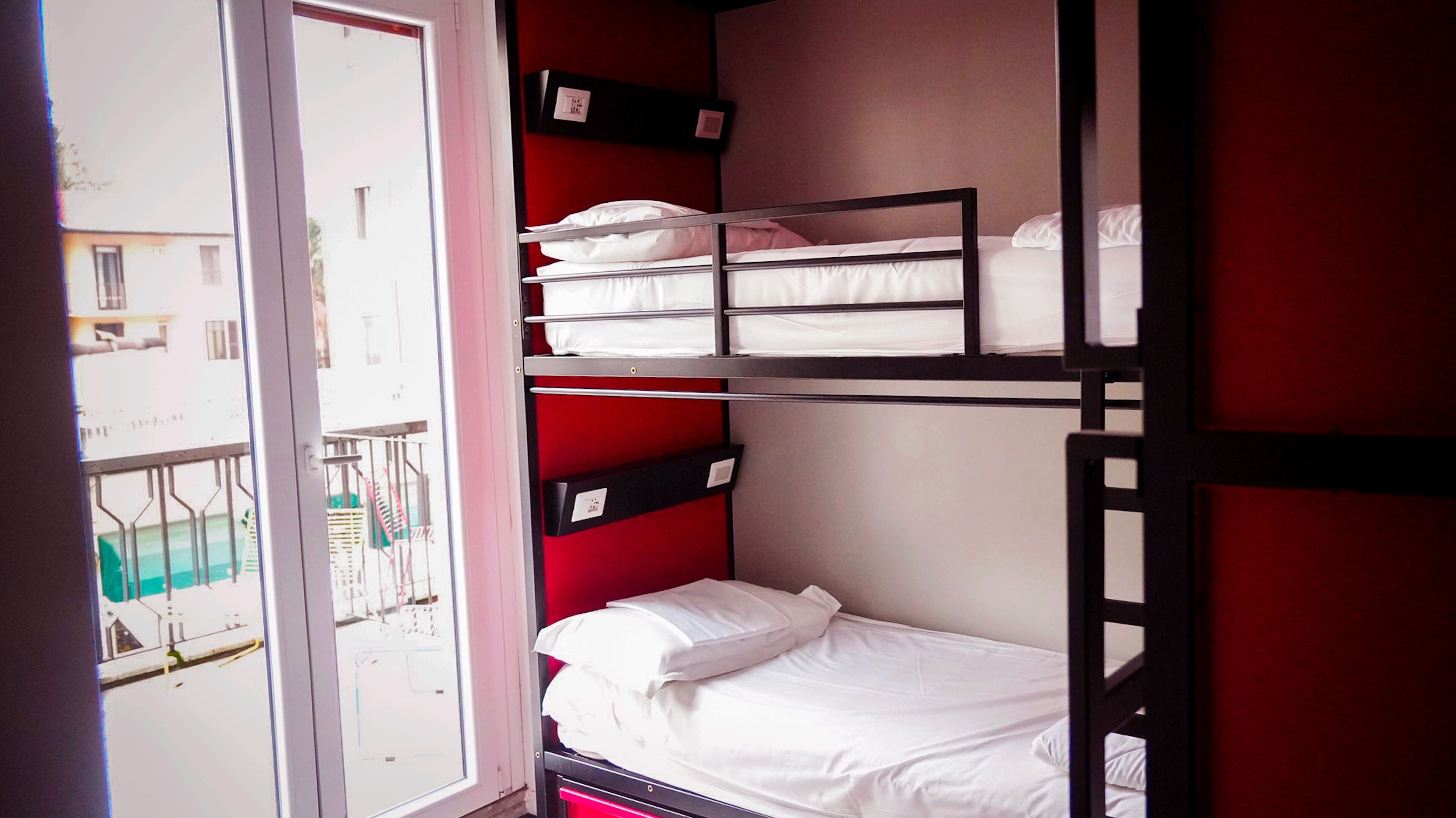 Une chambre de dortoir avec des lits superposés, une fenêtre et une vue sur l’extérieur.