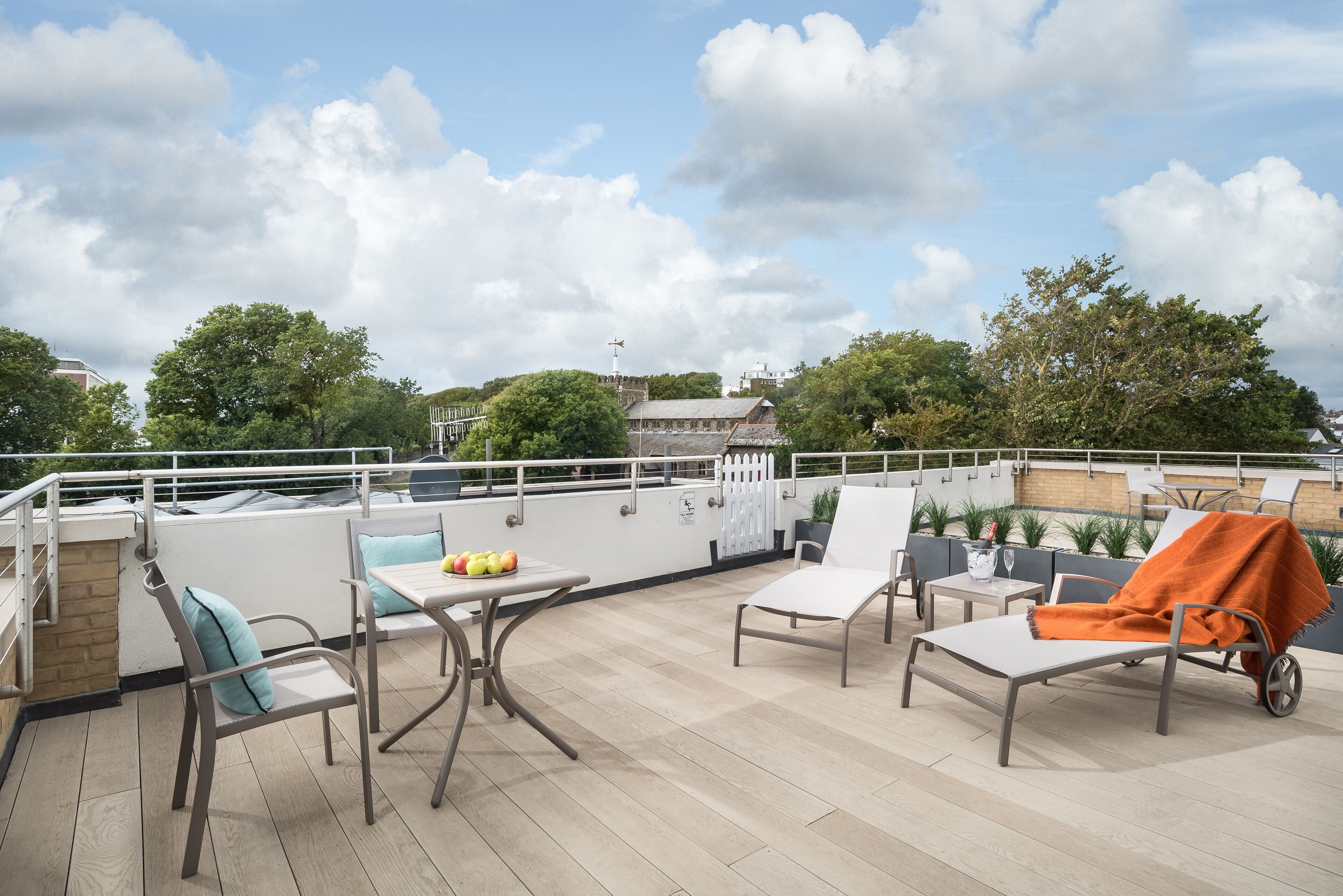 A rooftop terrace with outdoor seating, a table with fruits, and a view of the cityscape.