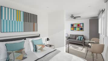 Ein modernes Hotelzimmer mit einem großen Bett, einer Couch, einem kleinen Tisch und einem Deckenventilator.