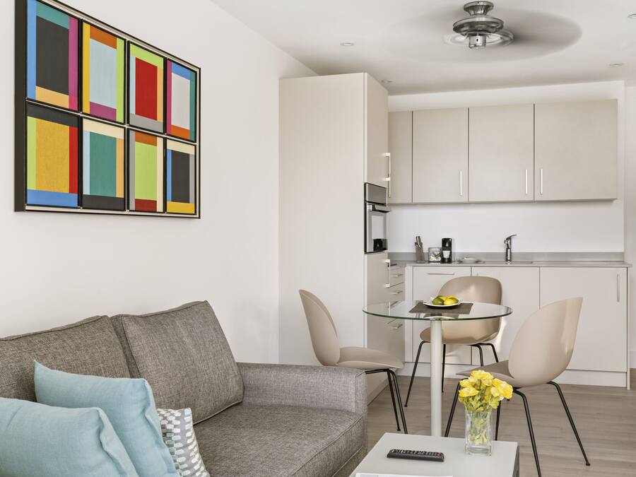 Uma sala de estar moderna com um sofá cinzento, uma mesa de centro e um quadro abstrato colorido na parede.