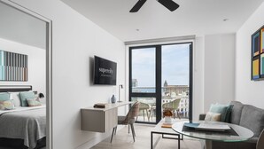 A modern apartment with a bed, a desk, a glass table, and a sofa.