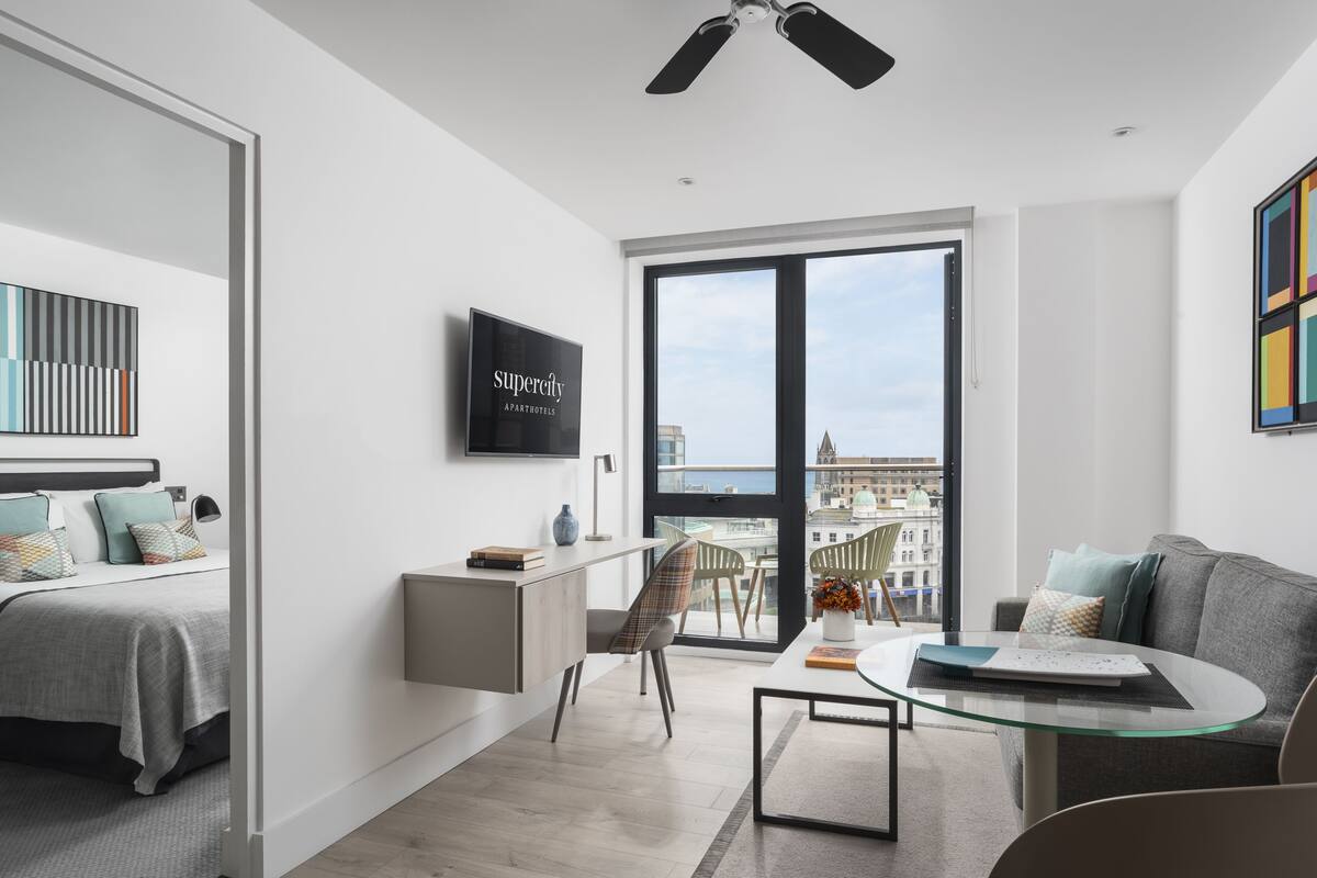 Een modern appartement met een bed, een bureau, een glazen tafel en een bank.