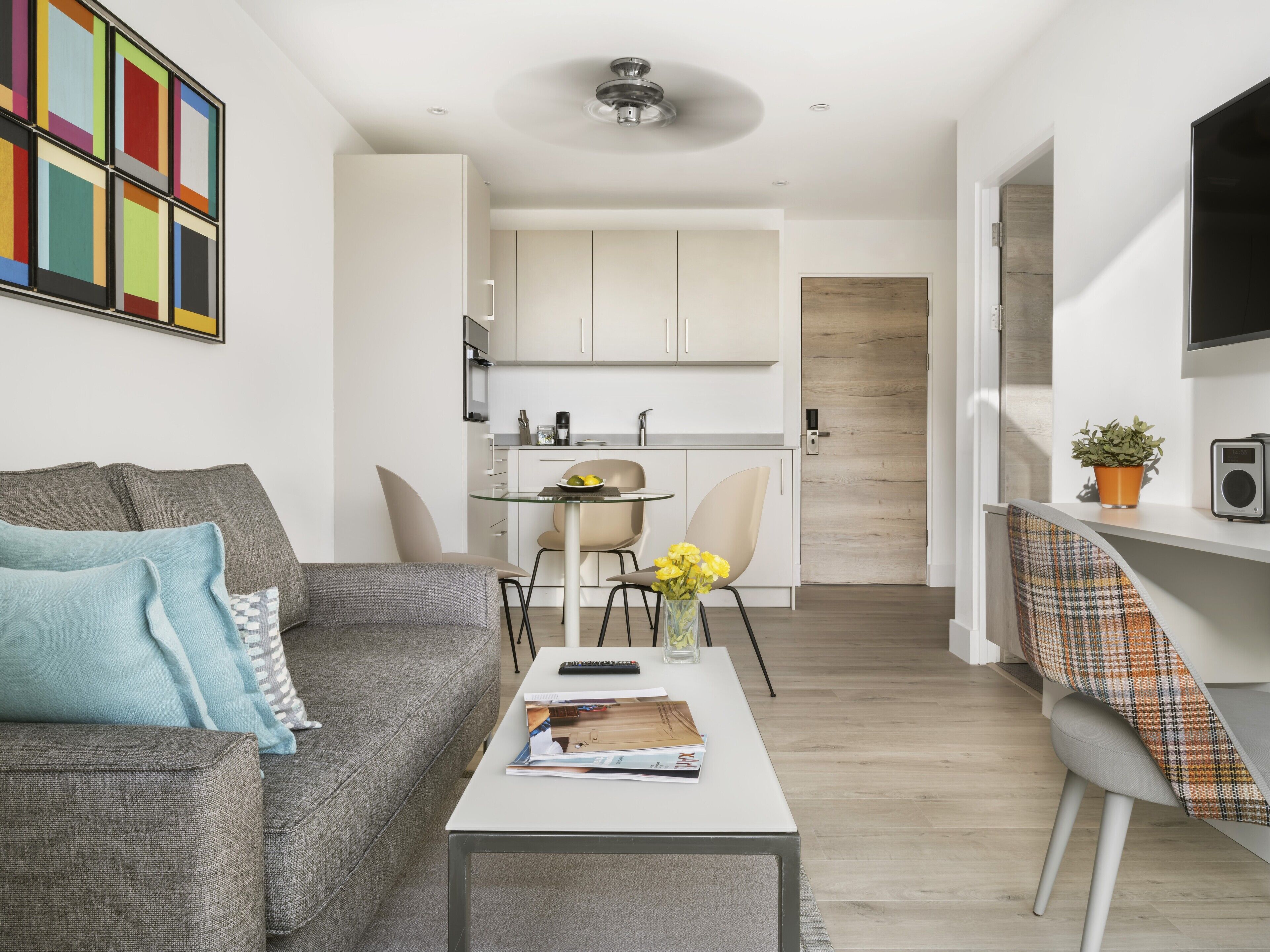 A modern living room with a grey sofa, a coffee table, and a dining area with a small table and chairs.