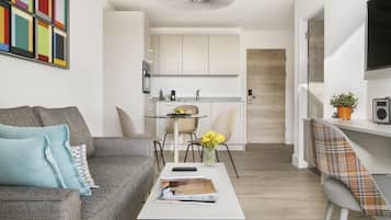 Una sala de estar moderna con un sofá gris, una mesa de centro y un comedor con una mesa pequeña y sillas.