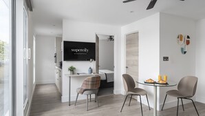 A modern kitchen with a dining area, a ceiling fan, and a TV displaying 'superecity apartments'.