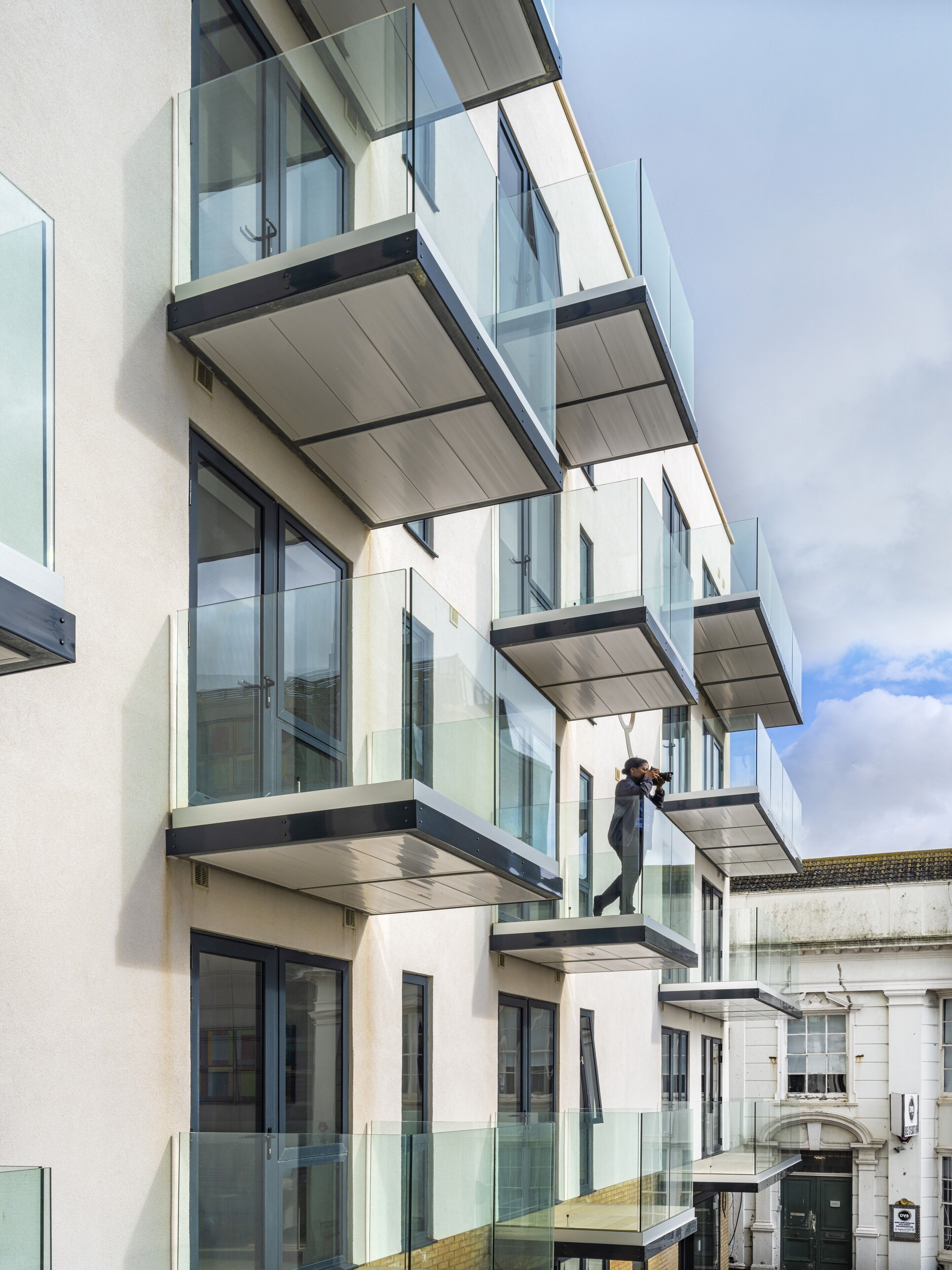Un immeuble à plusieurs étages doté de grandes fenêtres et d’un balcon.