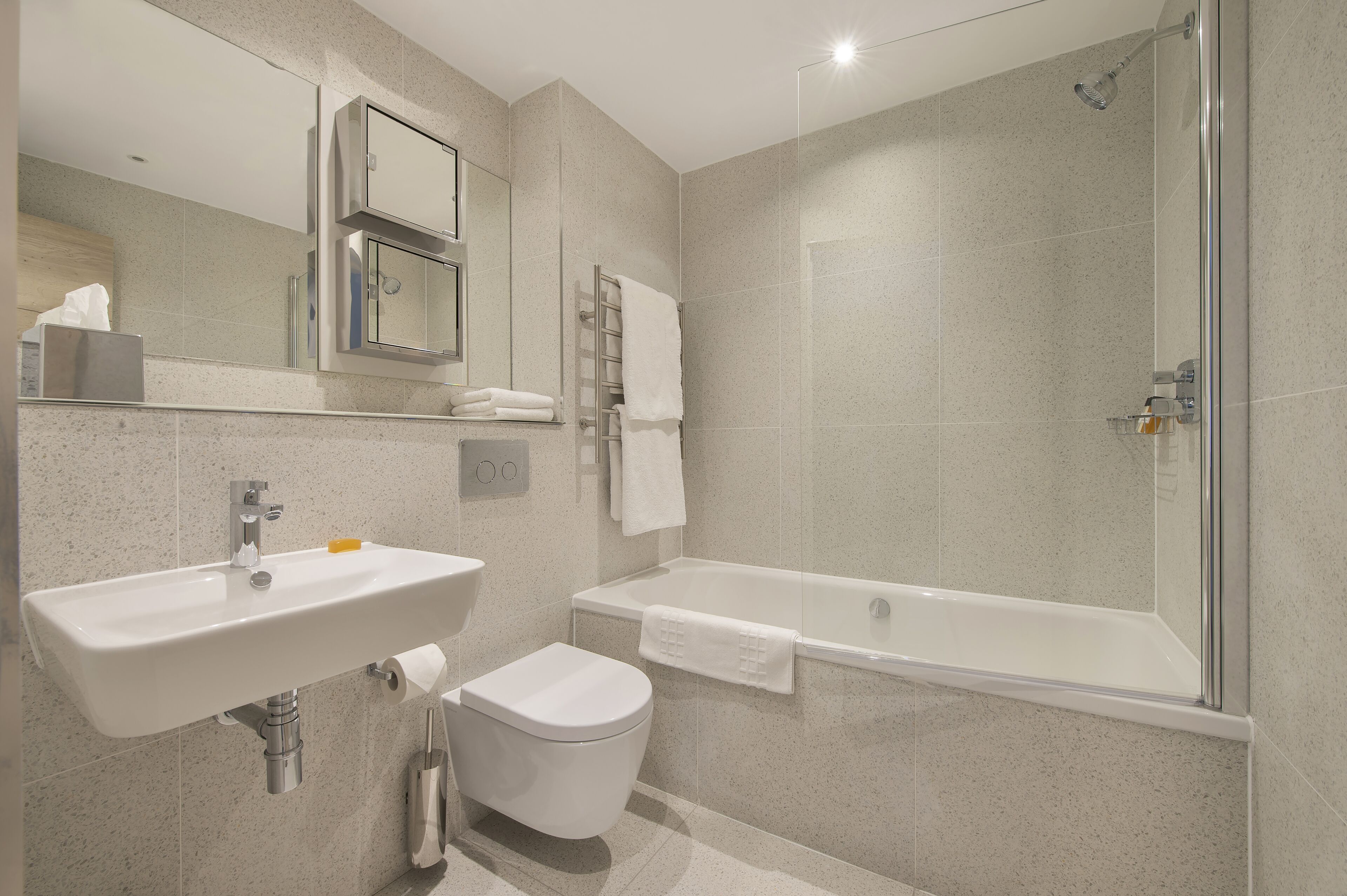 A modern bathroom with a sink, toilet, and bathtub.