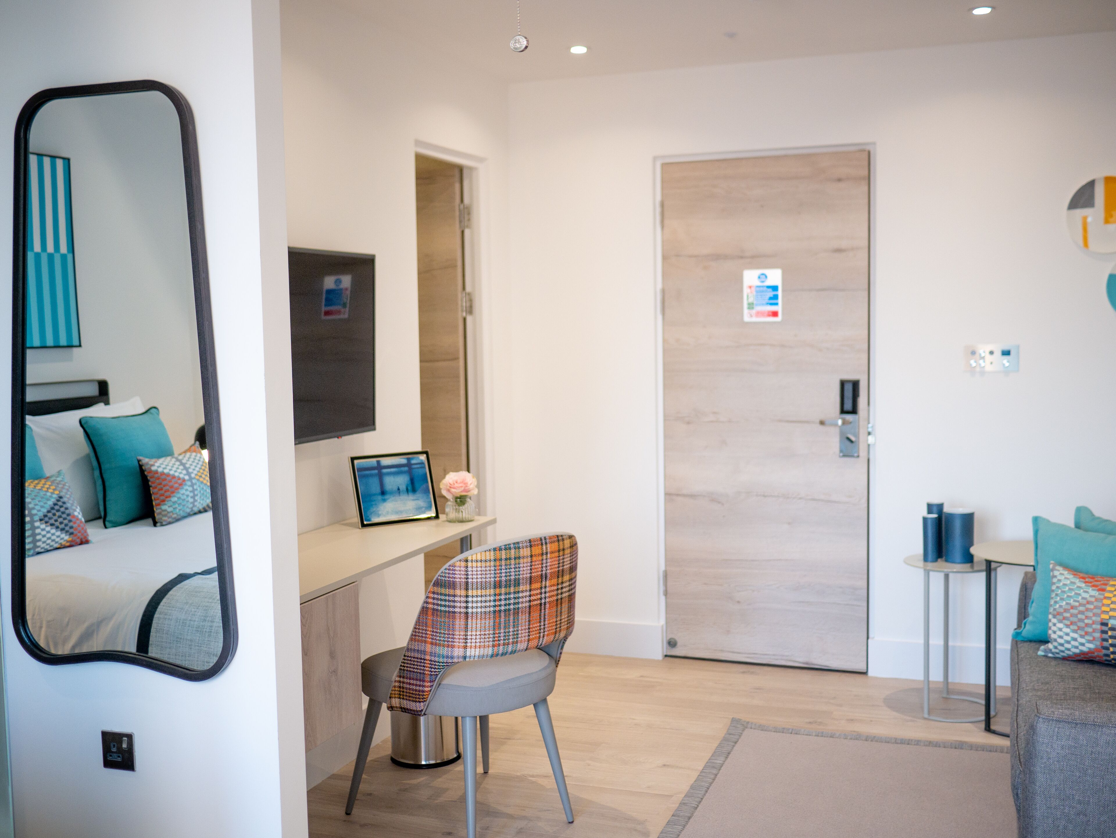 Une chambre d’hôtel moderne équipée d’un lit, d’un bureau, d’une chaise, d’un miroir et d’une porte.