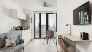 A modern, well-lit living area with a sofa, a dining table, and a kitchen area.