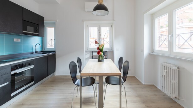 A modern kitchen with a dining area, featuring a wooden table, black chairs, and a hanging light fixture. - Roman Residenza : Bright, Quiet, and Modern in the Center of Rome (Roma)