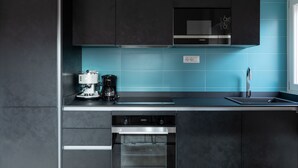 A modern kitchen with dark cabinets, a built-in oven, a coffee maker, and a microwave. - Roman Residenza : Bright, Quiet, and Modern in the Center of Rome (Roma)