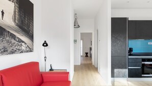 A modern living space with a red sofa, a black floor lamp, and a kitchen with blue tiles. - Roman Residenza : Bright, Quiet, and Modern in the Center of Rome (Roma)