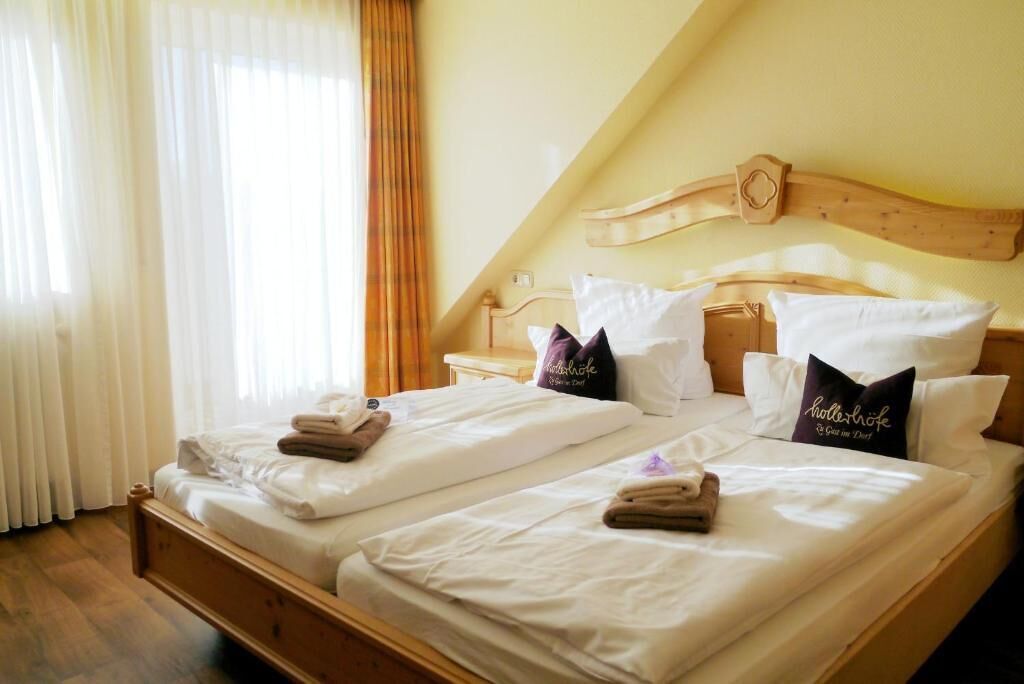A hotel room with two beds, each with neatly folded towels and pillows, and a wooden headboard.
