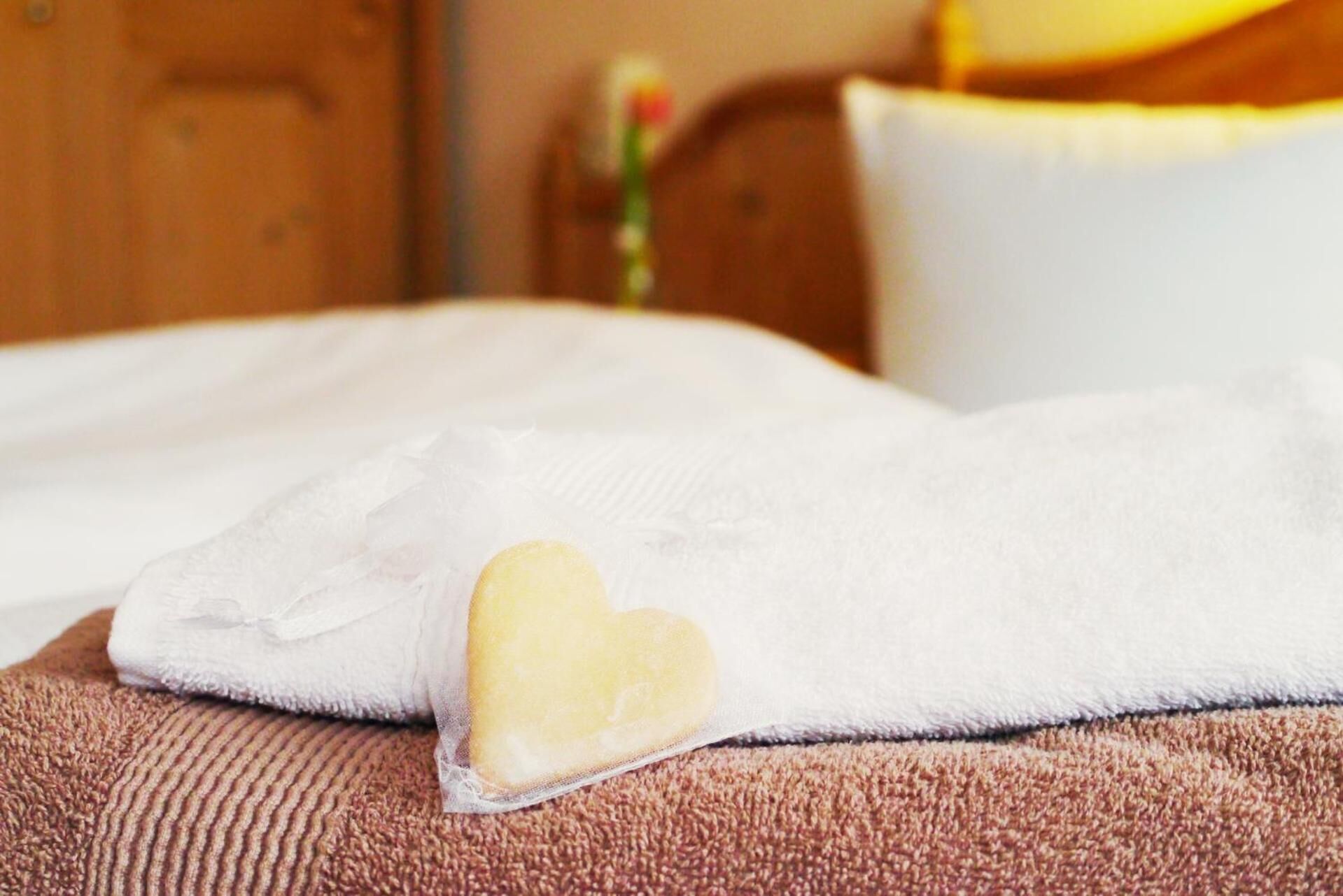 A bed with a white blanket and a heart-shaped pillow.