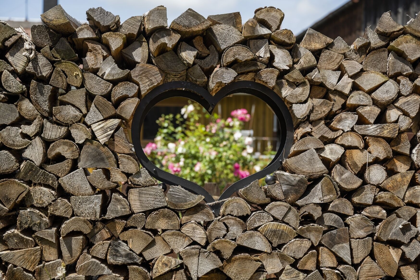 A heart-shaped window framed by stacked logs.
