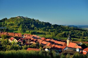 A town with red-roofed buildings, a prominent church tower, and a hill with a structure on top. - Landgasthof Zum Hirschen (Kemnath)