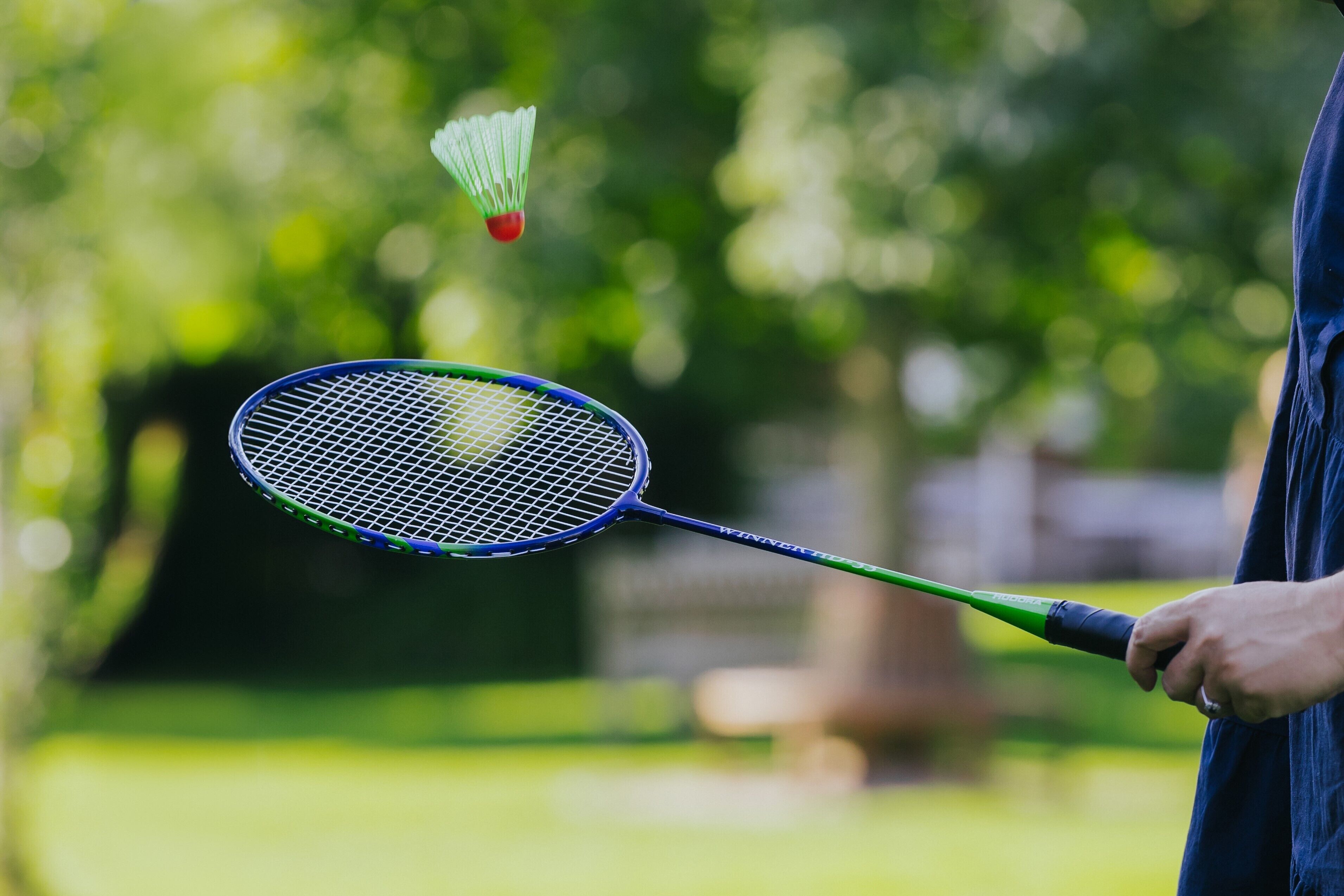 A person holding a badminton racket with a shuttlecock in motion.