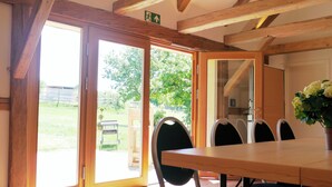 A room with a wooden table and chairs, large sliding glass doors leading to an outdoor area with greenery. - Landgasthof Zum Hirschen (Kemnath)